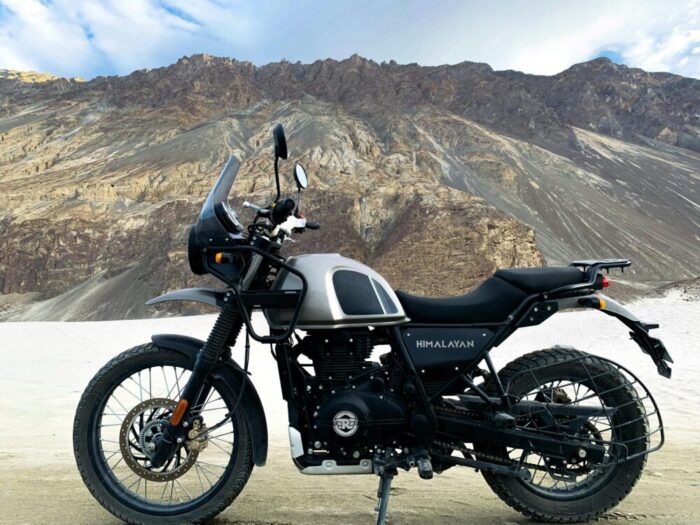 A rugged Royal Enfield Himalayan motorbike parked against the scenic mountains of Jammu.