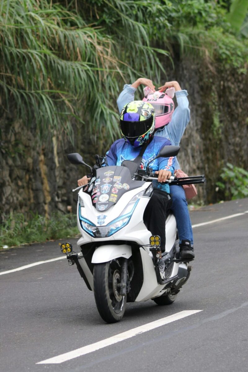 Two people riding a decorated motorbike on a winding road in Sagñay, Bicol.